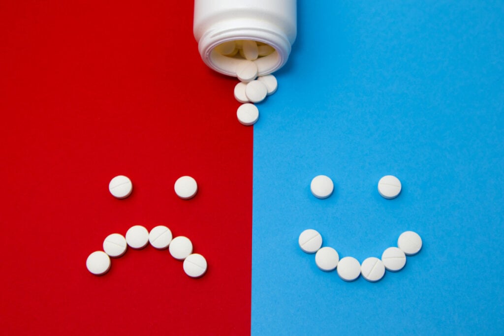 Pílulas de remédio formando um rosto triste e outro feliz