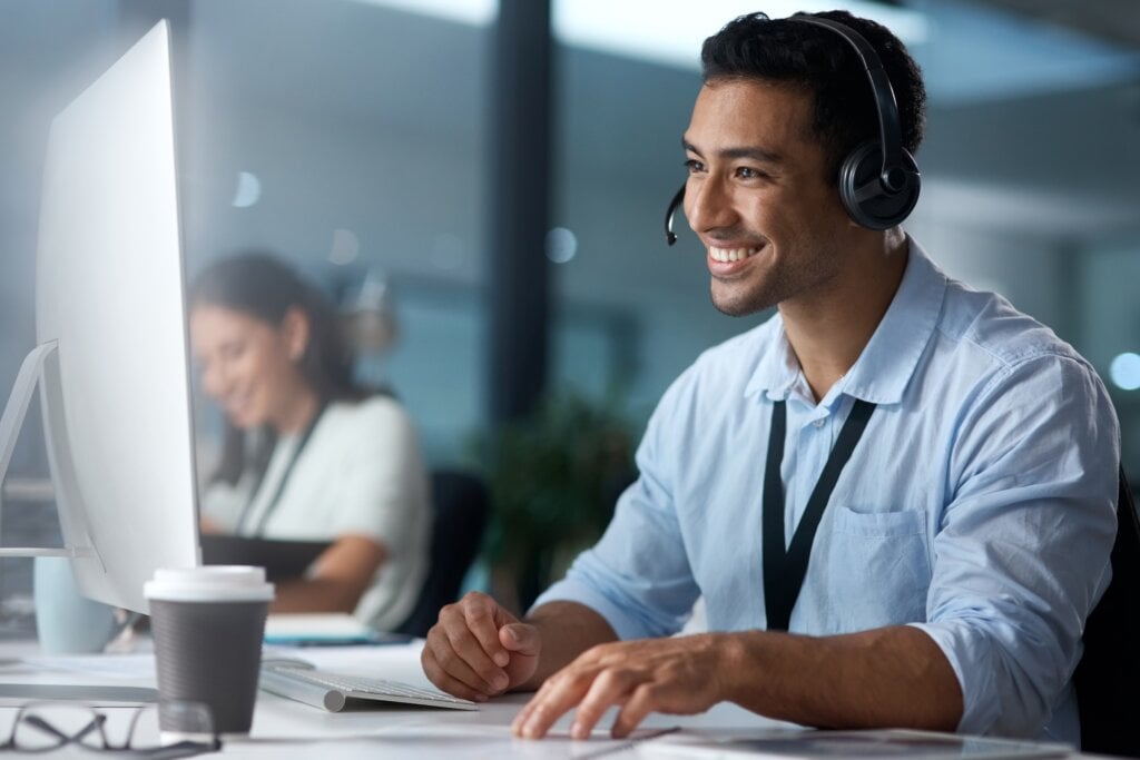 Homem sentado usando headfone e mexendo no computador