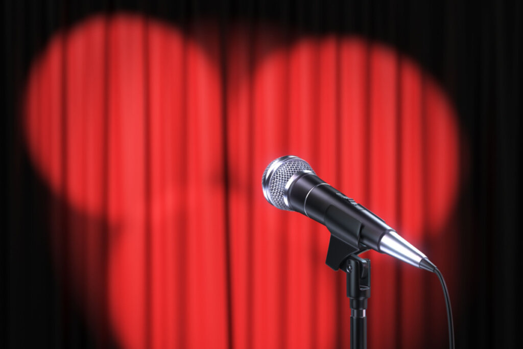 Microfone posicionado em frente à cortina vermelha com iluminação redonda.