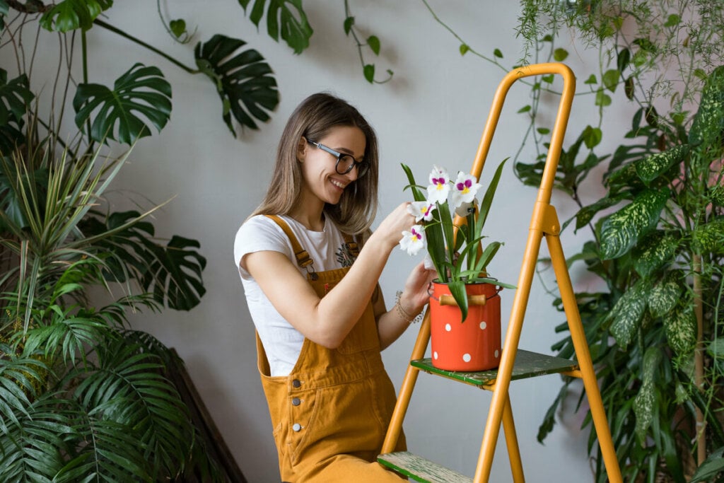 Mulher sorridente cuidando de uma orquídea