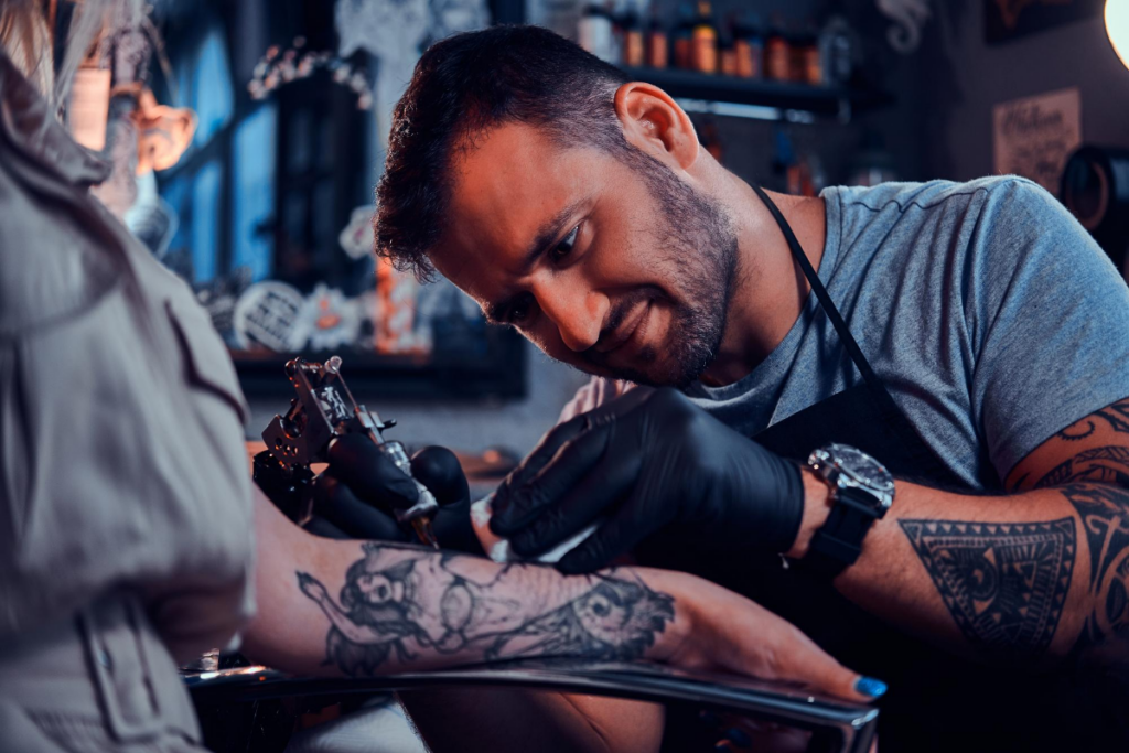 Tatuador fazendo tatuagem no braço de uma mulher 