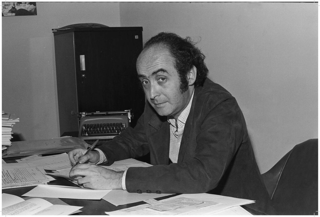 Jornalista Vladimir Herzog escrevendo em mesa com vários papéis 