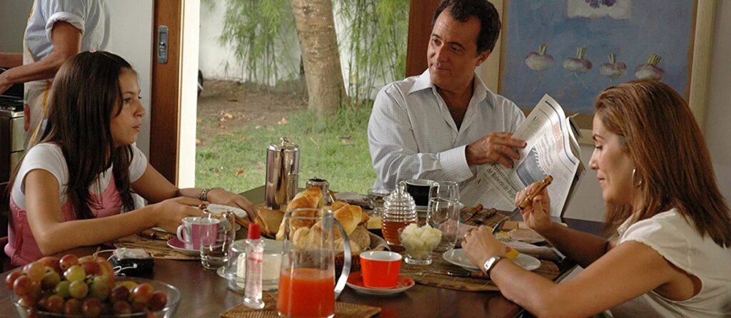 Imagem do filme "Se Eu Fosse Você" em que os personagens estão sentados em mesa de jantar