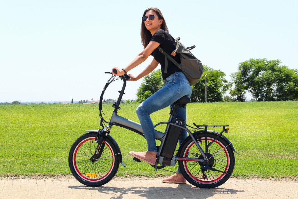 Mulhe de blusa preta e óculos de sol andando de bicicleta elétrica