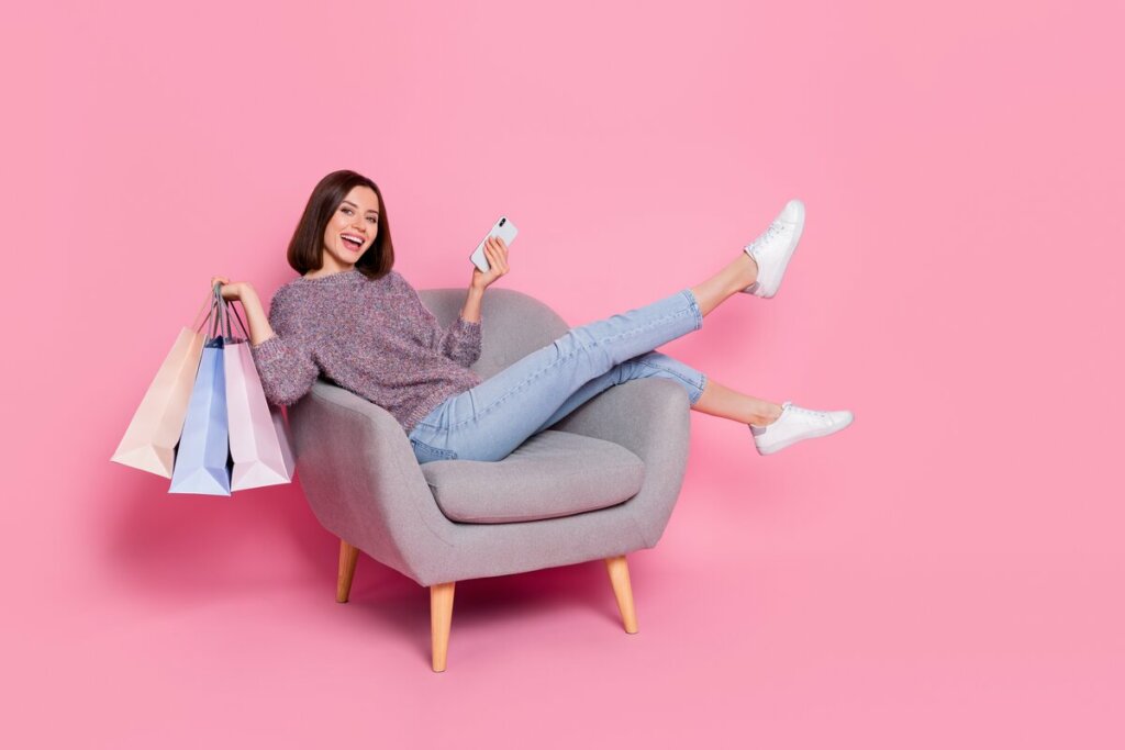 Mulher sentada sorrindo segurando sacola de compras