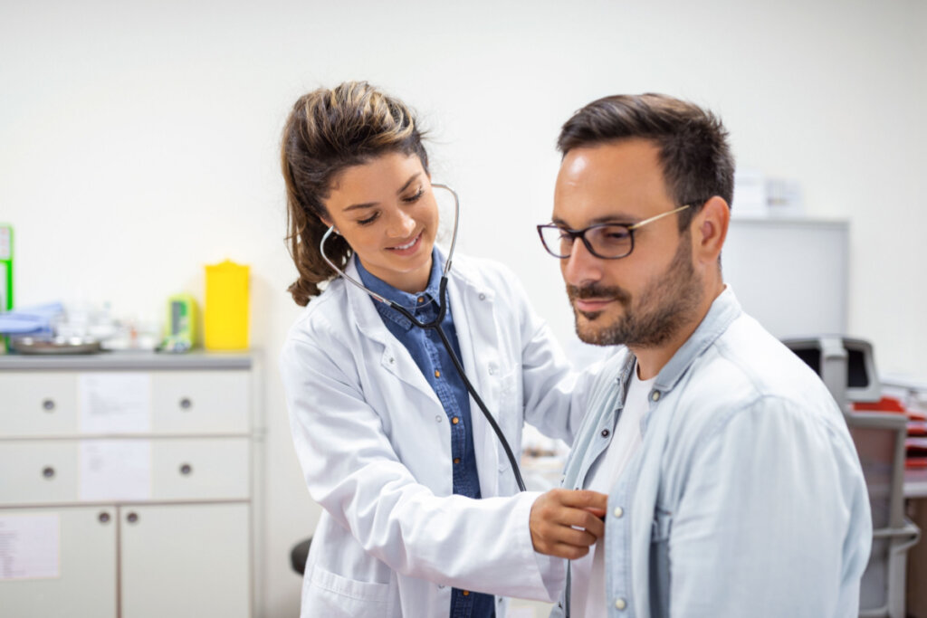 Jovem médica usando um estetoscópio para ouvir os batimentos cardíacos do paciente