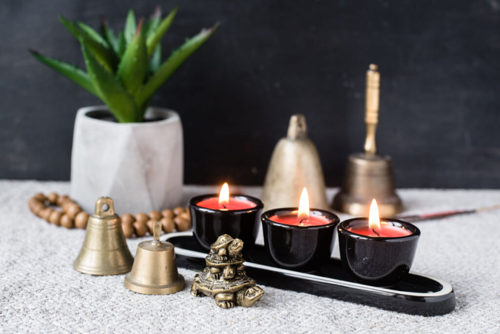 Composição com símbolos budistas e feng shui: yin yang, tartarugas, velas aromáticas, rosários, sinos de mão e planta em vaso
