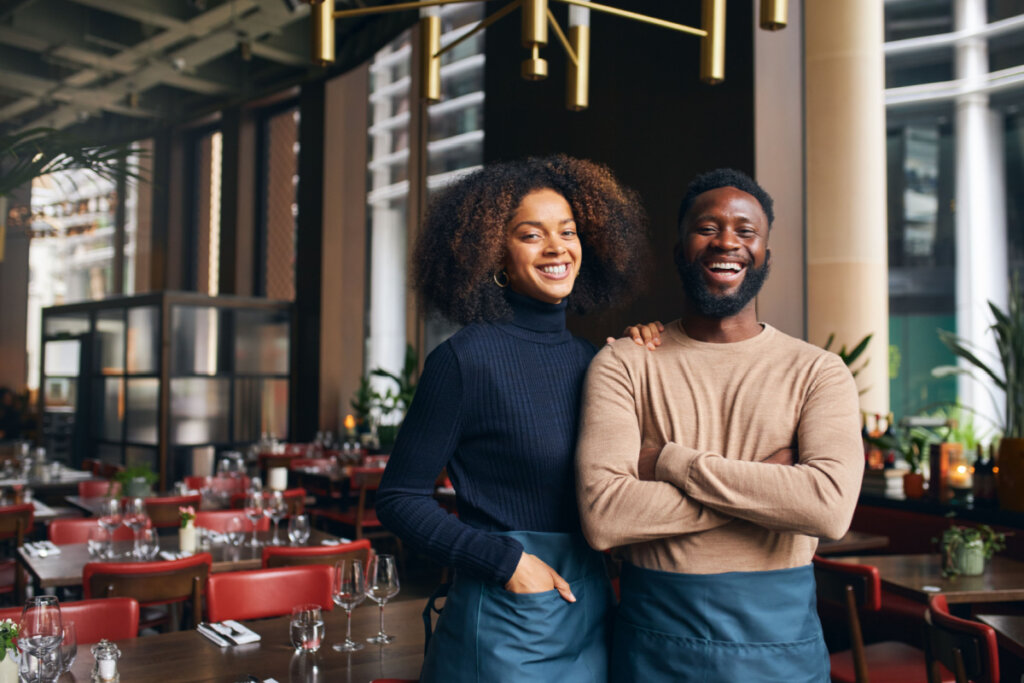 Homem e mulher em pé em um restaurante e sorrindo um ao lado do outro