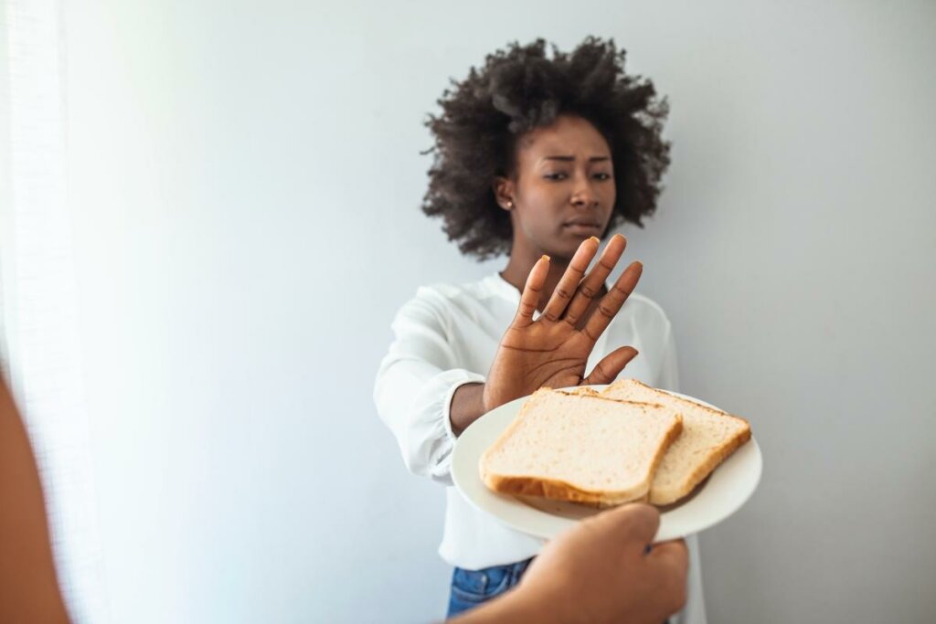 Mulher recusando fatias de pão com a mão 