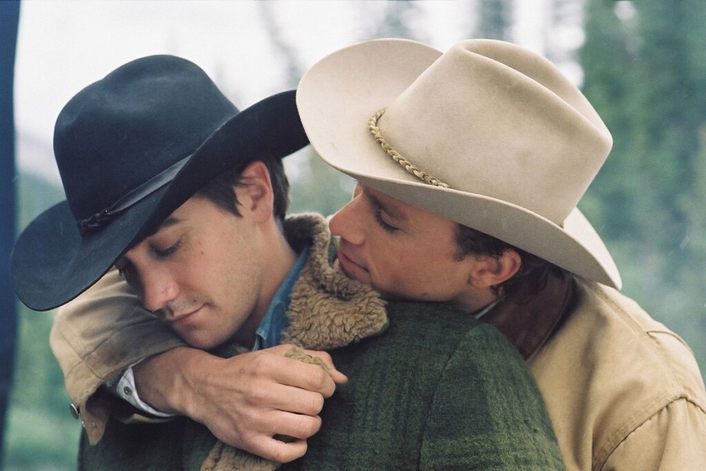 Dois atores vestidos de cowboys abraçados em filme Brokeback Mountain.