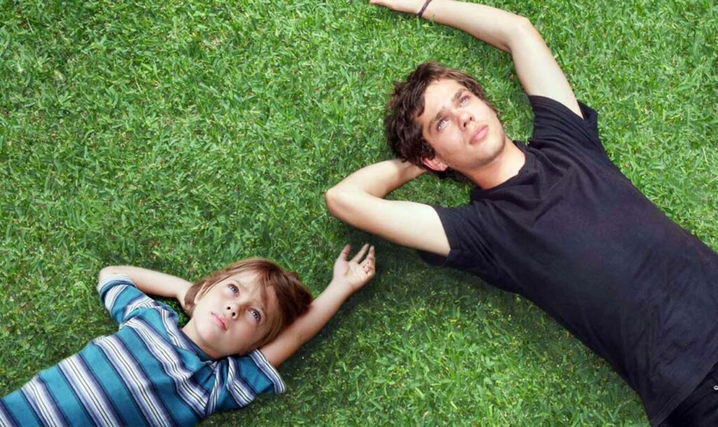 Capa do filme "Boyhood". Uma montagem do ator enquanto criança e jovem adulto deitado na grama.