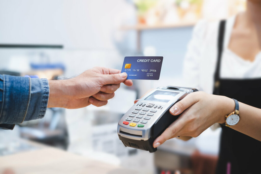 Pessoa segurando cartão de crédito para passar em uma máquina de cartão 
