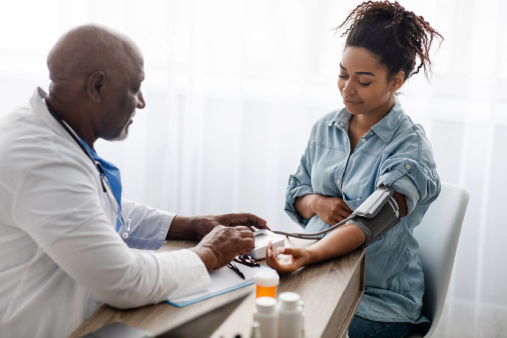 Médico medindo pressão arterial de uma mulher grávida