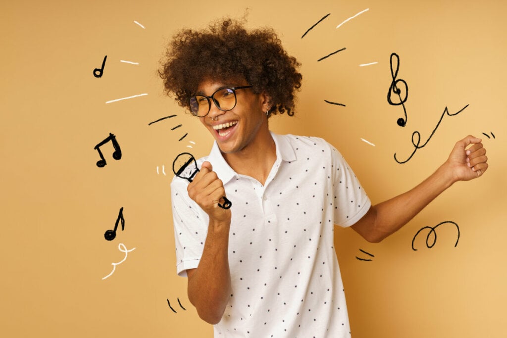 Homem de blusa branca e óculos sorrindo e segurando uma ilustração de microfone