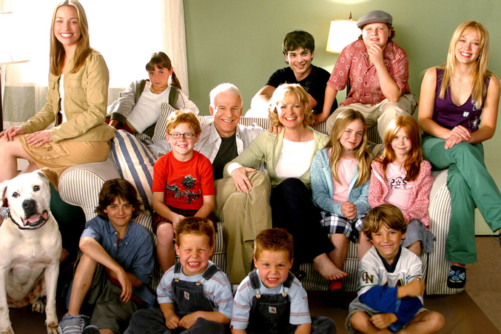 Imagem do filme "Doze é demais", toda a família reunida e sorridente em sofá. 
