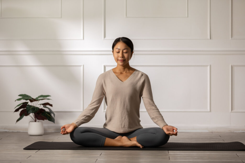 Mulher sentada no tapete respirando com pose de lótus de meditação