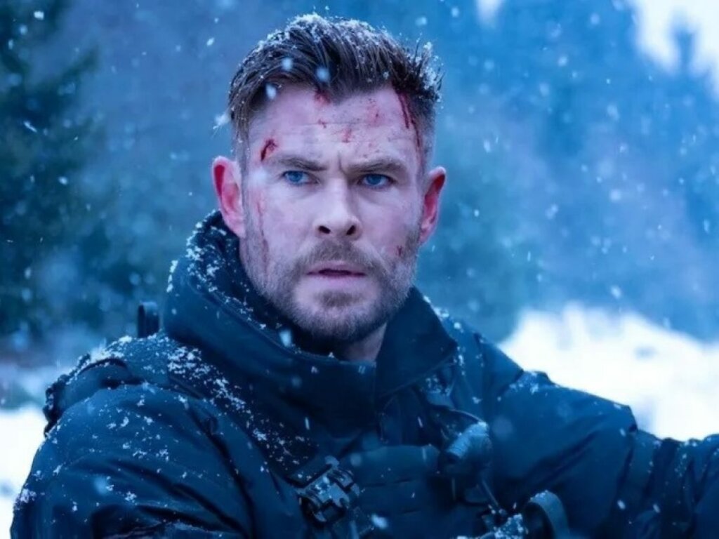 Imagem do personagem de Chris Hemsworth no filme "O Resgate" em meio à neve e com o rosto machucado