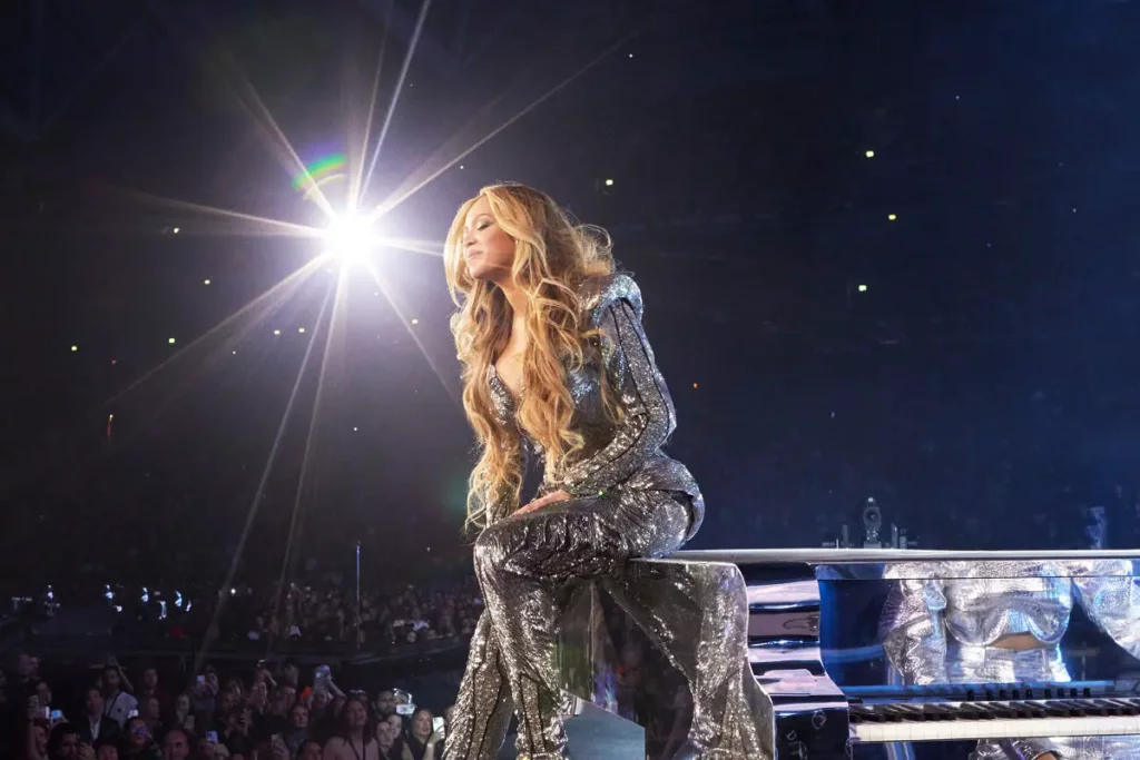 Cantora Beyoncé sentada em piano durante show, iluminada por holofote