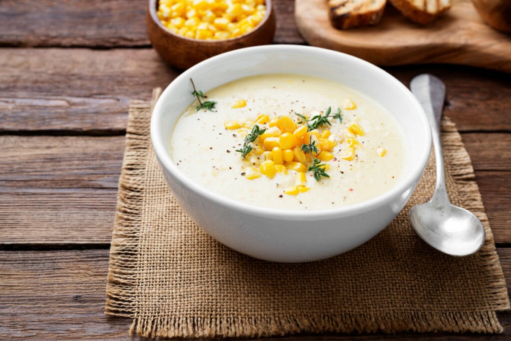 Caldo branco com milho-verde em recipiente branco