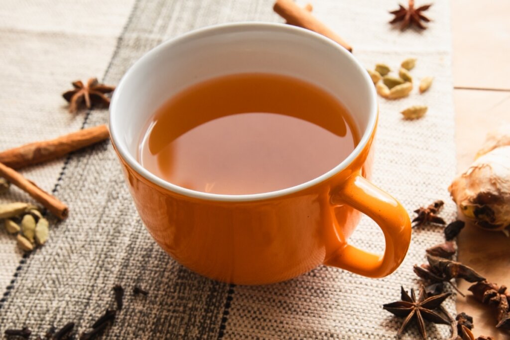 Xícara laranja com chá em cima de uma mesa de madeira 