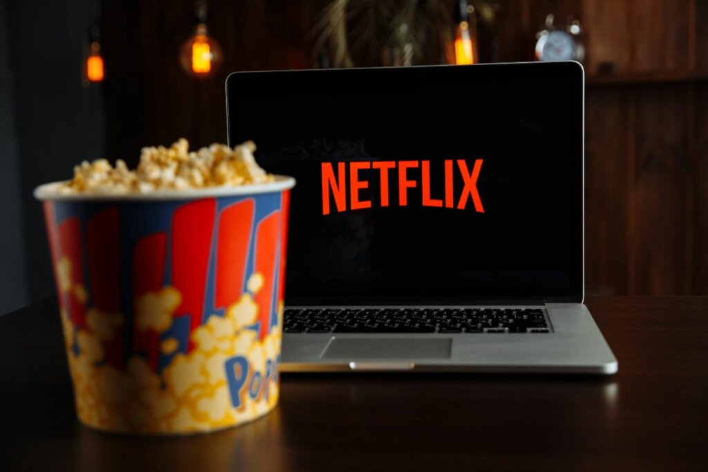 Logo da Netflix em uma televisão e um balde de pipoca em cima de uma mesa