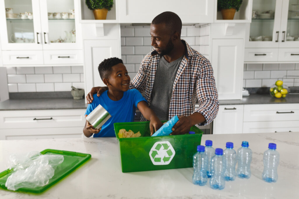 Pai e filho na cozinha conversando e separando lixo para reciclagem