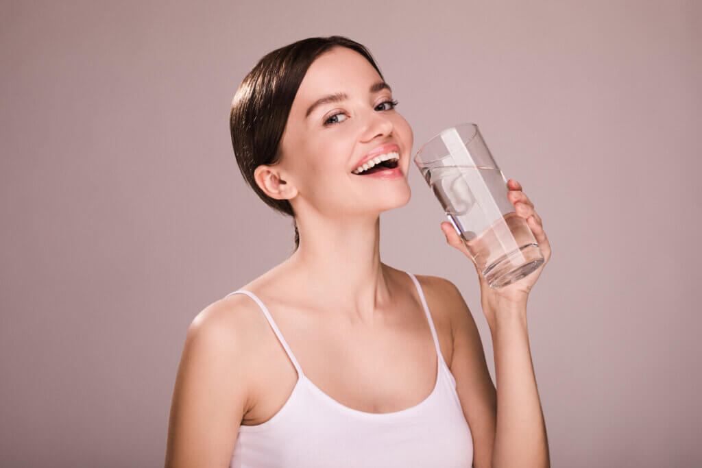 Mulher sorridente com copo de água na mão