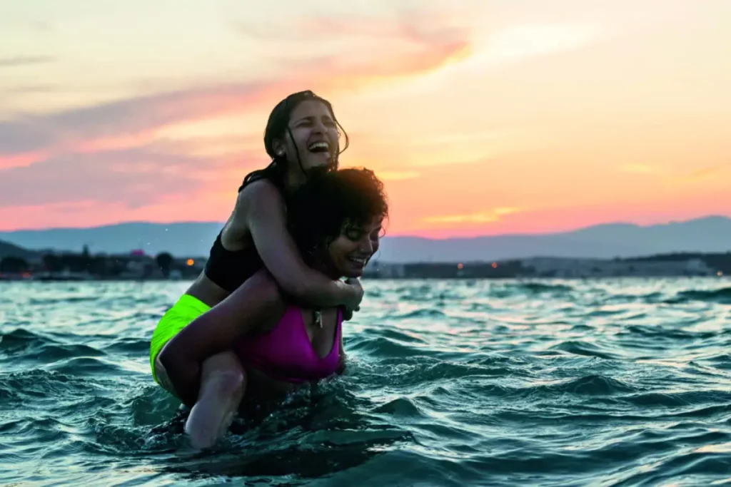 Cena do filme As Nadadoras. Duas irmãs abraçadas sorrindo dentro do mar.