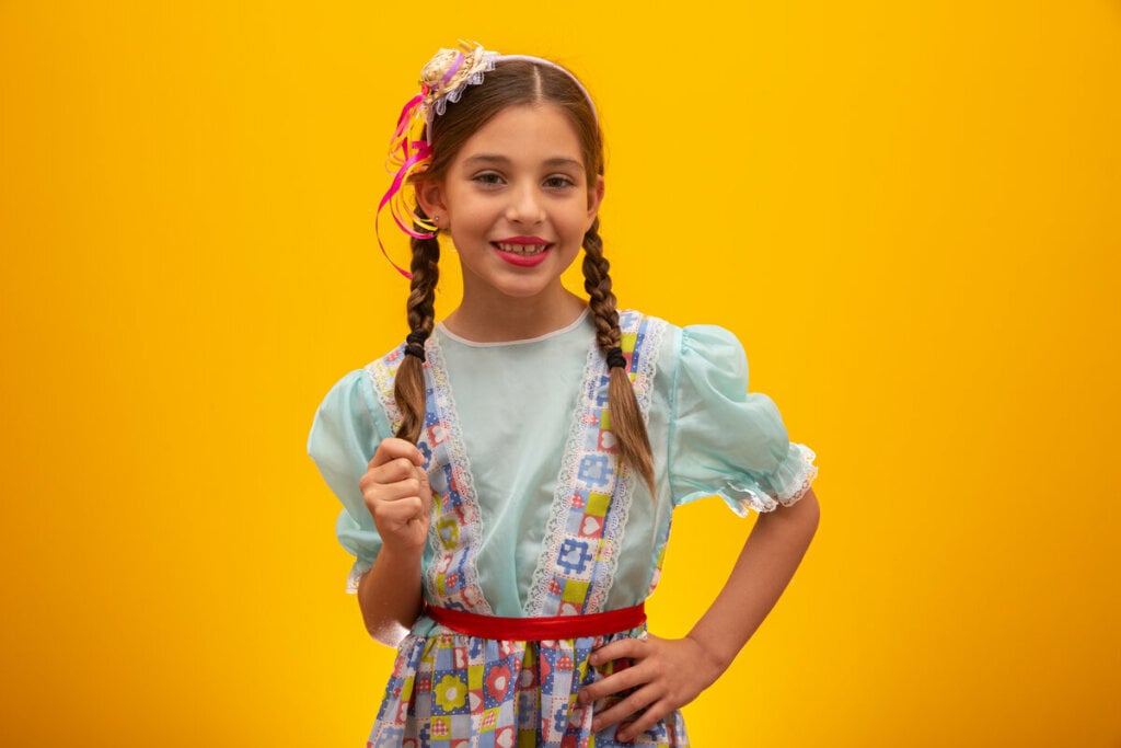 Menina com roupa de festa junina e mini chápeu sorrindo