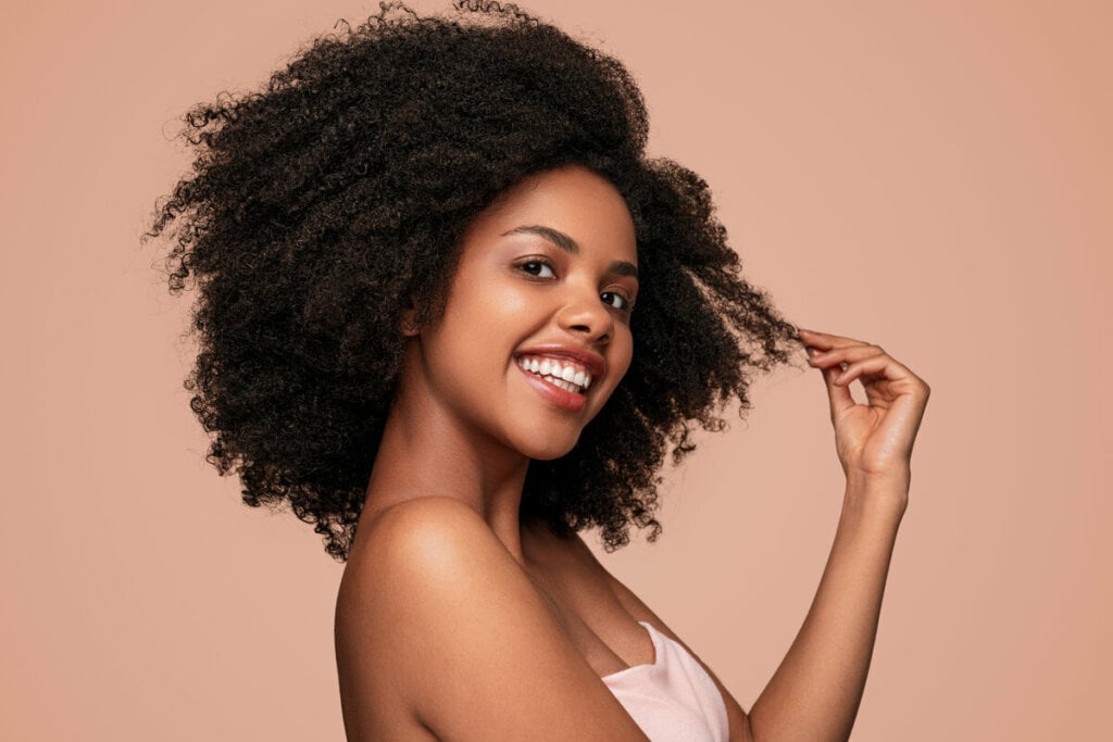 Mulher sorrindo segurando uma mexa de cabelo