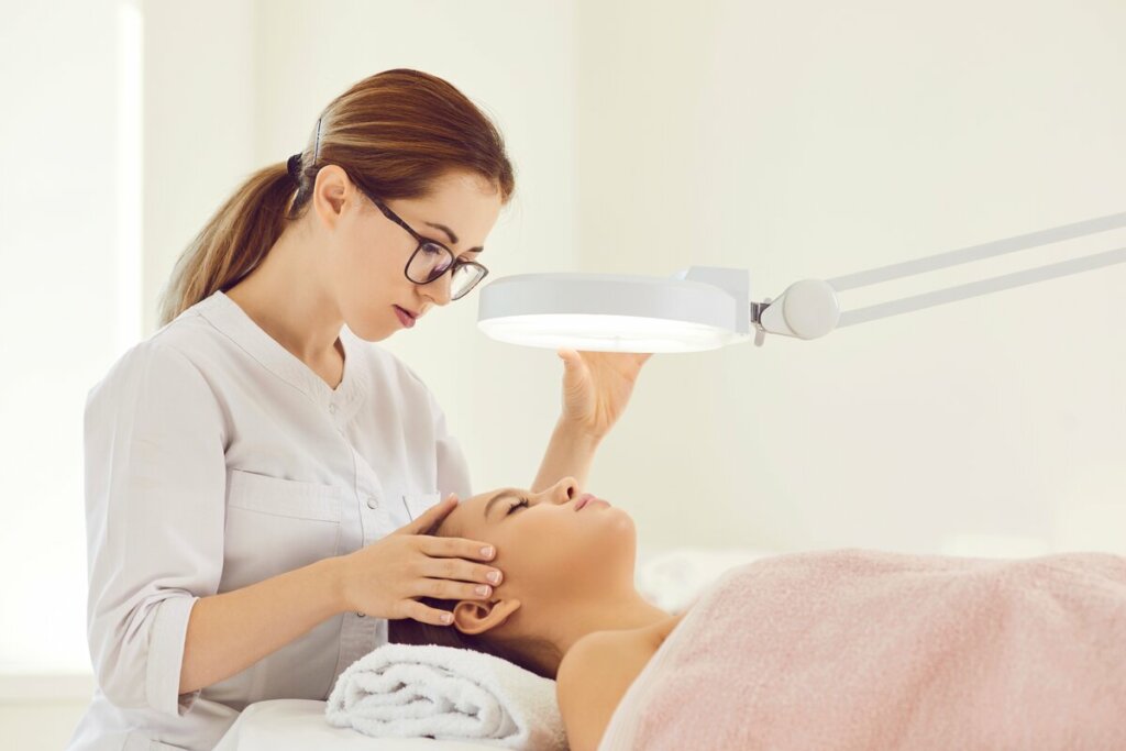 Dermatologista examinando o rosto de uma mulher 