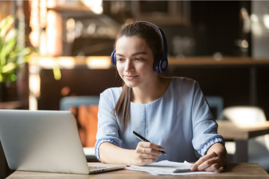 Menina de fones de ouvido estudando em frente ao computador