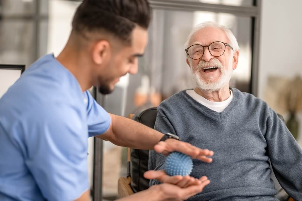 Paciente recebendo massagem na mão com uma bola de fisioterapia