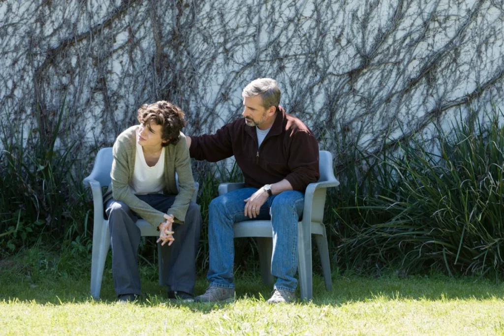 Cena do filme "Beautiful Boy", com os personagens pai e filho sentados em banco no jardim.