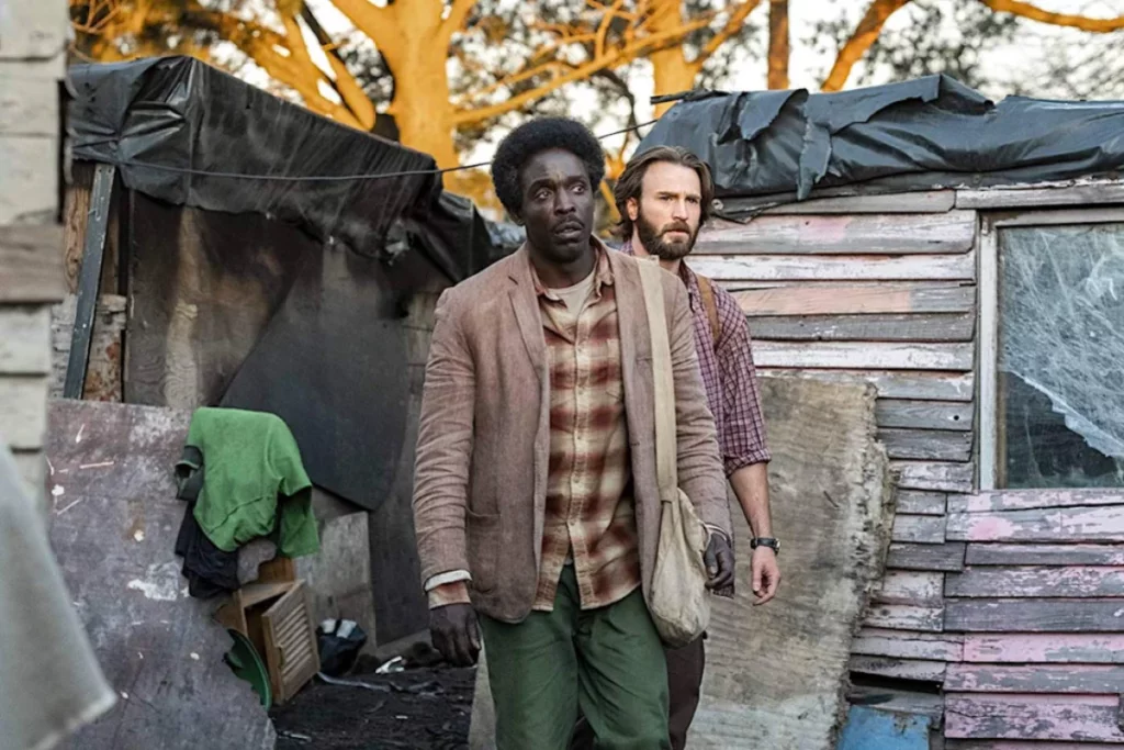 Cena do filme Missão no Mar Vermelho, dois homens em meio a moradias insalubres.