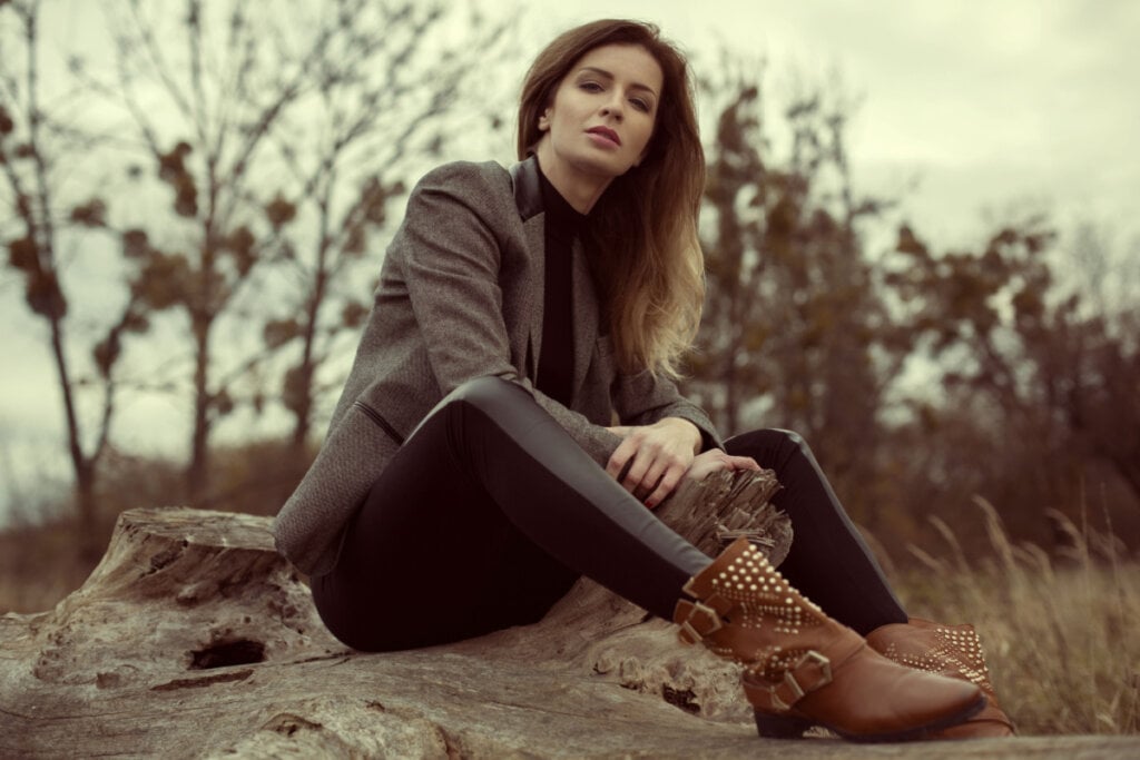 Mulher sentada em uma pedra ao ar livre e usando uma bota western