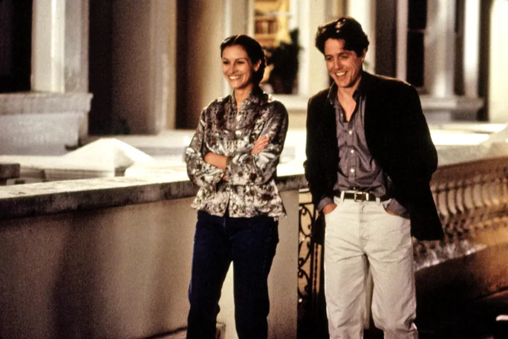 Cena do filme "Um lugar chamado Notting Hill" com os protagonistas andando na rua à noite e rindo.
