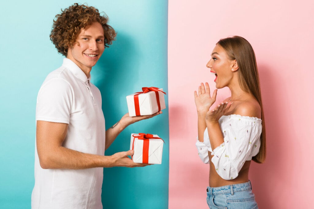 Homem segurando dois presentes e uma mulher surpresa