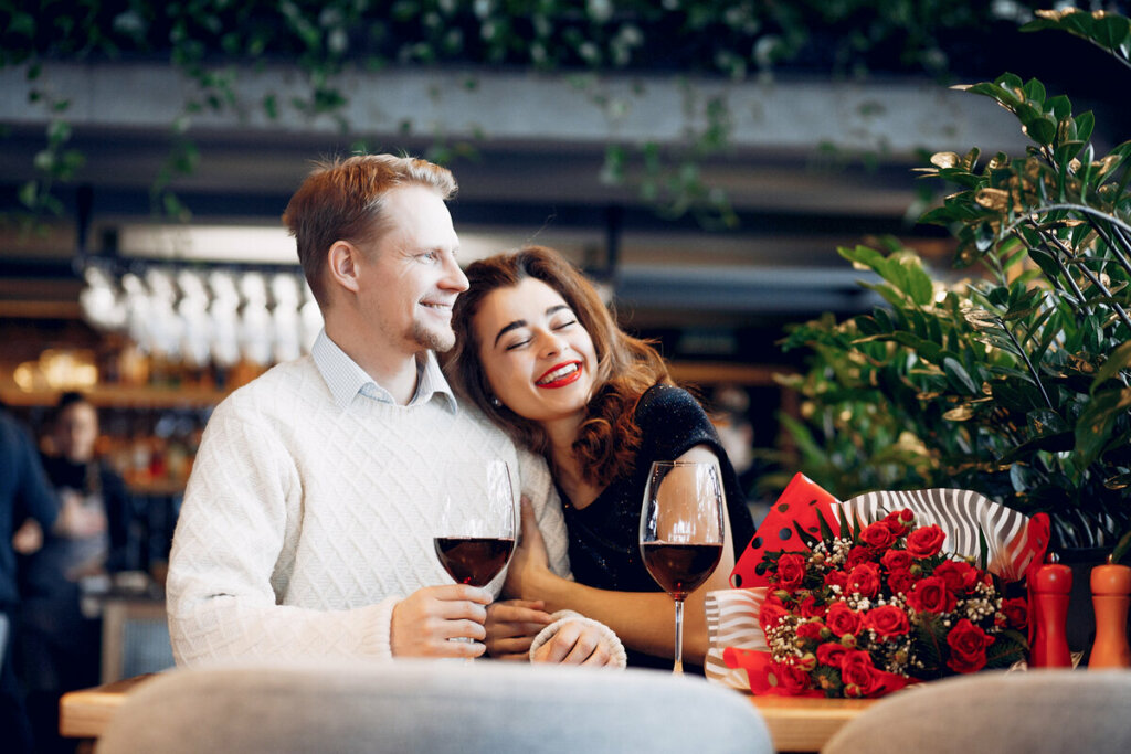 Homem e mulher abraçados e sentados tomando vinho