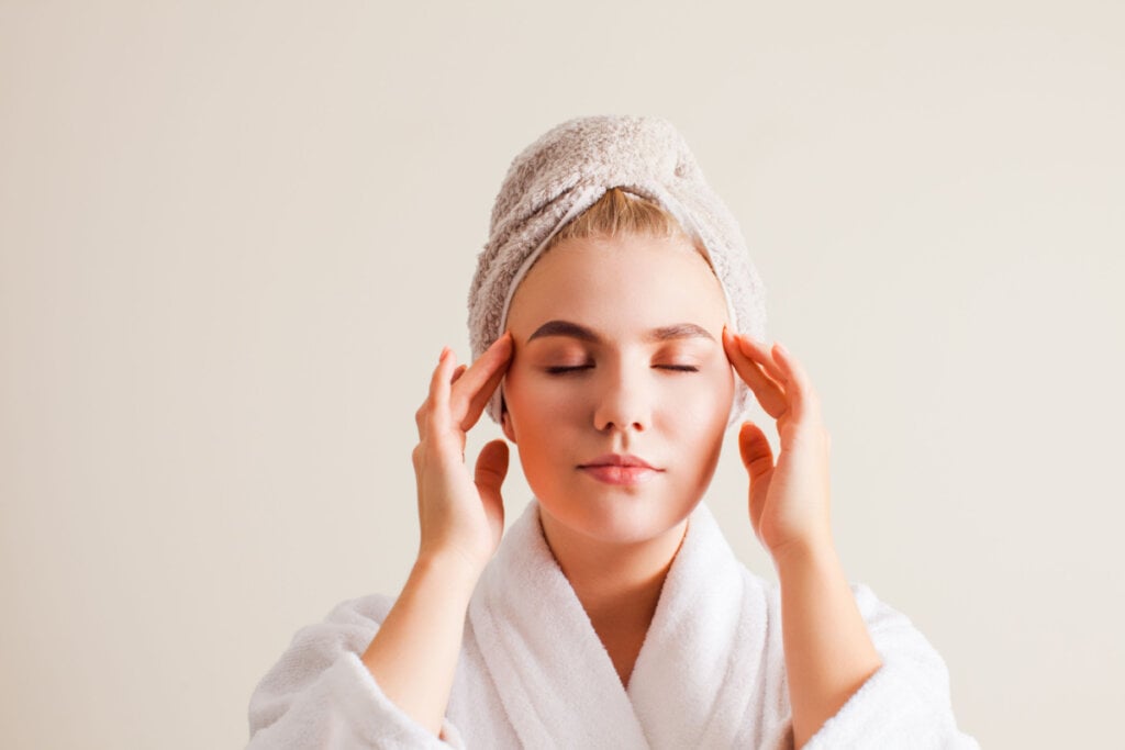 Mulher fazendo automassagem facial em casa