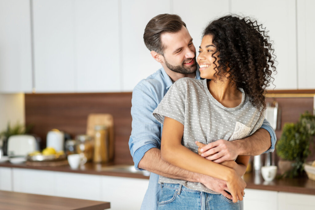 Homem sorridente abraçando sua mulher por trás