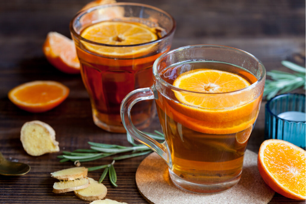 Xícara de vidro transparente com chá e rodelas de laranja 