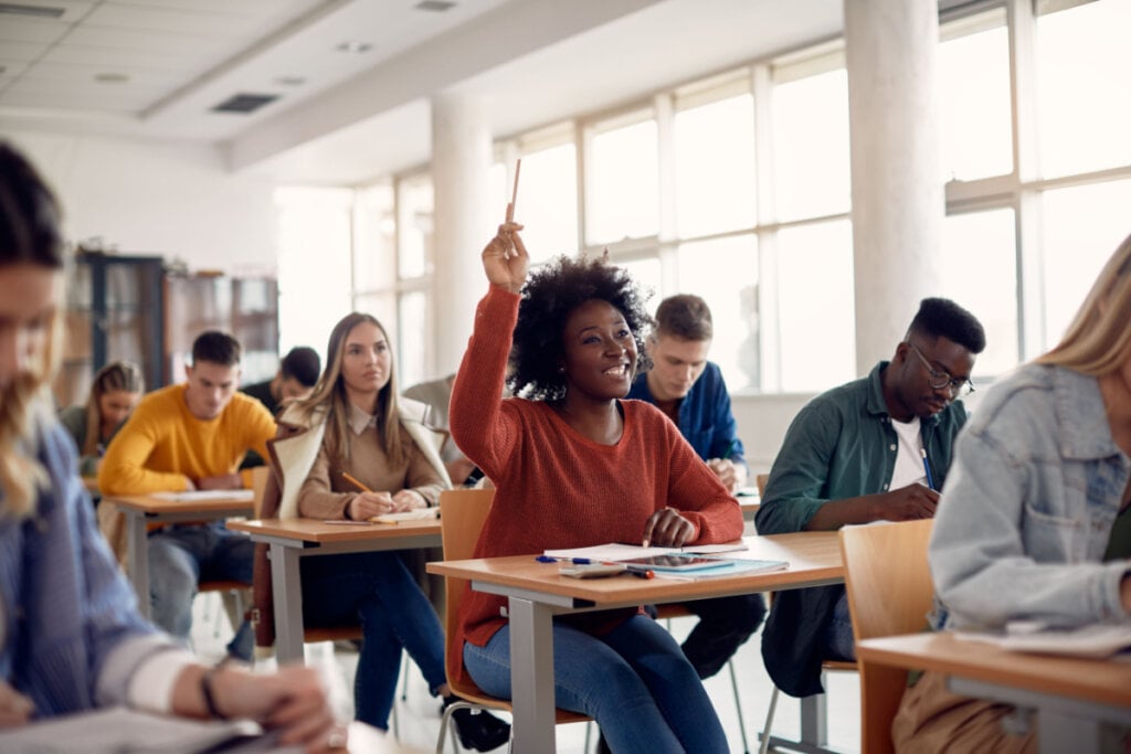 Estudante levantando a mão para fazer uma pergunta durante uma aula