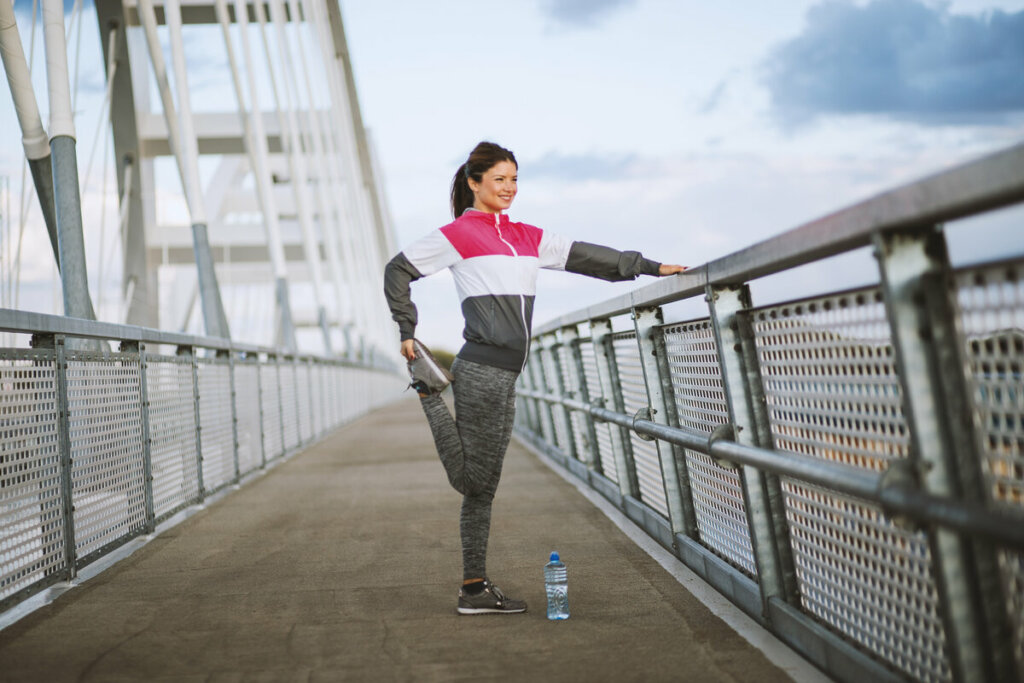 Mulher com roupa de frio fazendo exercícios em uma ponte