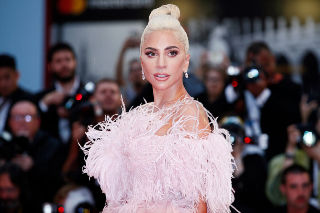 Cantora Lady Gaga posando para foto usando um vestido rosa com plumas