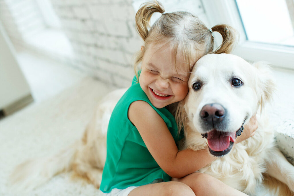 Menina de blusa verde abraçando um cachorro