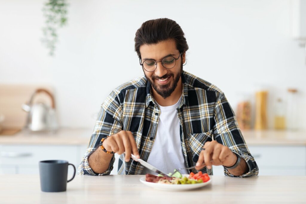 Homem vestindo blusa xadrez sentado comendo 