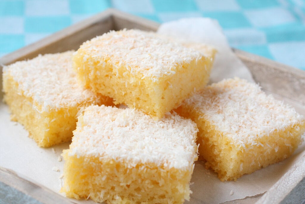 Pedaços de bolo de coco polvilhados com coco em cima de um prato branco