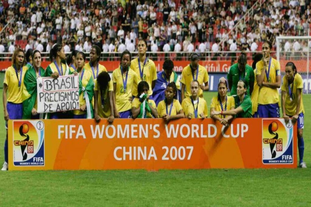 Jogadoras brasileiras com medalhas de prata atrás de placa da FIFA na Copa do Mundo Feminina em 2007.