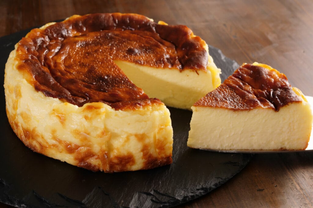 Cheesecake em cima de um recipiente preto com um pedaço cortado